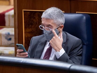 El ministro de Interior, Fernando Grande-Marlaska, observa su teléfono móvil en una sesión plenaria en el Congreso de los Diputados.