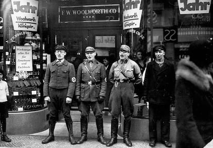 Nazis uniformados cantando ante un comercio judío durante un pogromo.