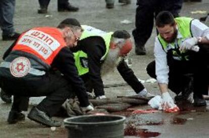 Varios ultraortodoxos judíos secan la sangre en el lugar del atentado.