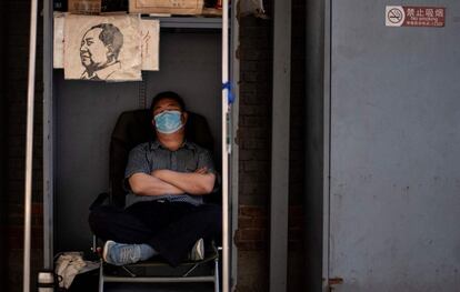 Un librero duerme mientras espera clientes en el mercado de antigüedades de Panjiayuan, en Pekín (China)