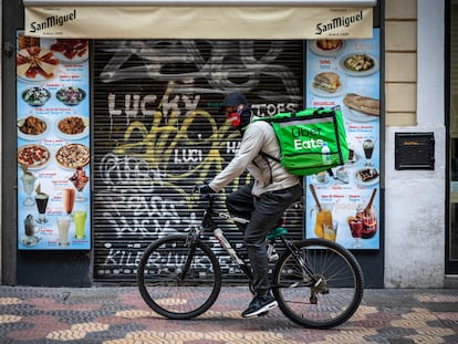 Un repartidor de Uber pasa por delante de una pequeña cafetería del centro de Valencia.