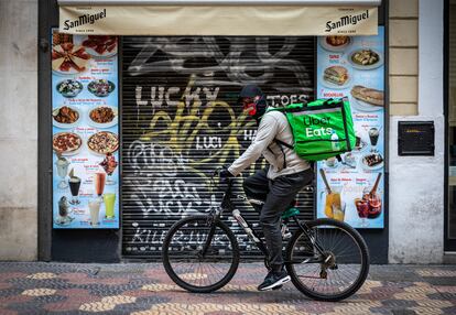 Un repartidor de Uber pasa por delante de una pequeña cafetería del centro de Valencia.