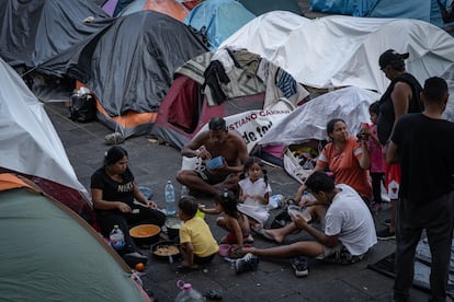 Una familia de migrantes come junto a las tiendas de campaña montadas en la Plaza de la Soledad. 