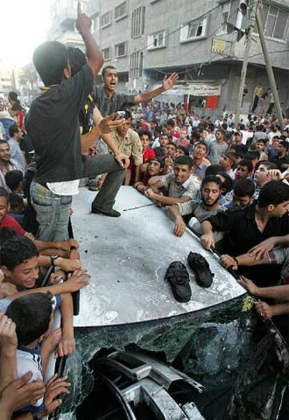 Palestinos protestan junto al coche atacado ayer en Gaza.