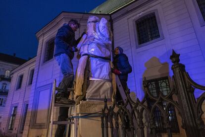 Dos voluntarios cubren las esculturas de la Catedral en Lviv. La mayoría del millón de desplazados a otros países que ha provocado la guerra han pasado por Lviv. En su estación de tren, edificio de 1904 de bello 'art nouveau', también se concentran estos días miles de estudiantes extranjeros, sobre todo de África y Asia, que huyen del conflicto.