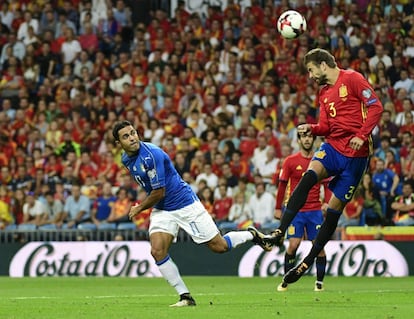 El defensa de España, Gerard Pique golpea la pelota junto al mediocampista italiano Eder.