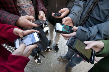 Jóvenes de un instituto barcelonés consultan las redes sociales a través del móvil.