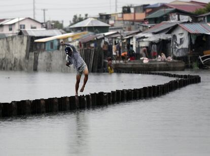 Un joven camina sobre un dique en la ciudad de Bacoor (Filipinas). 