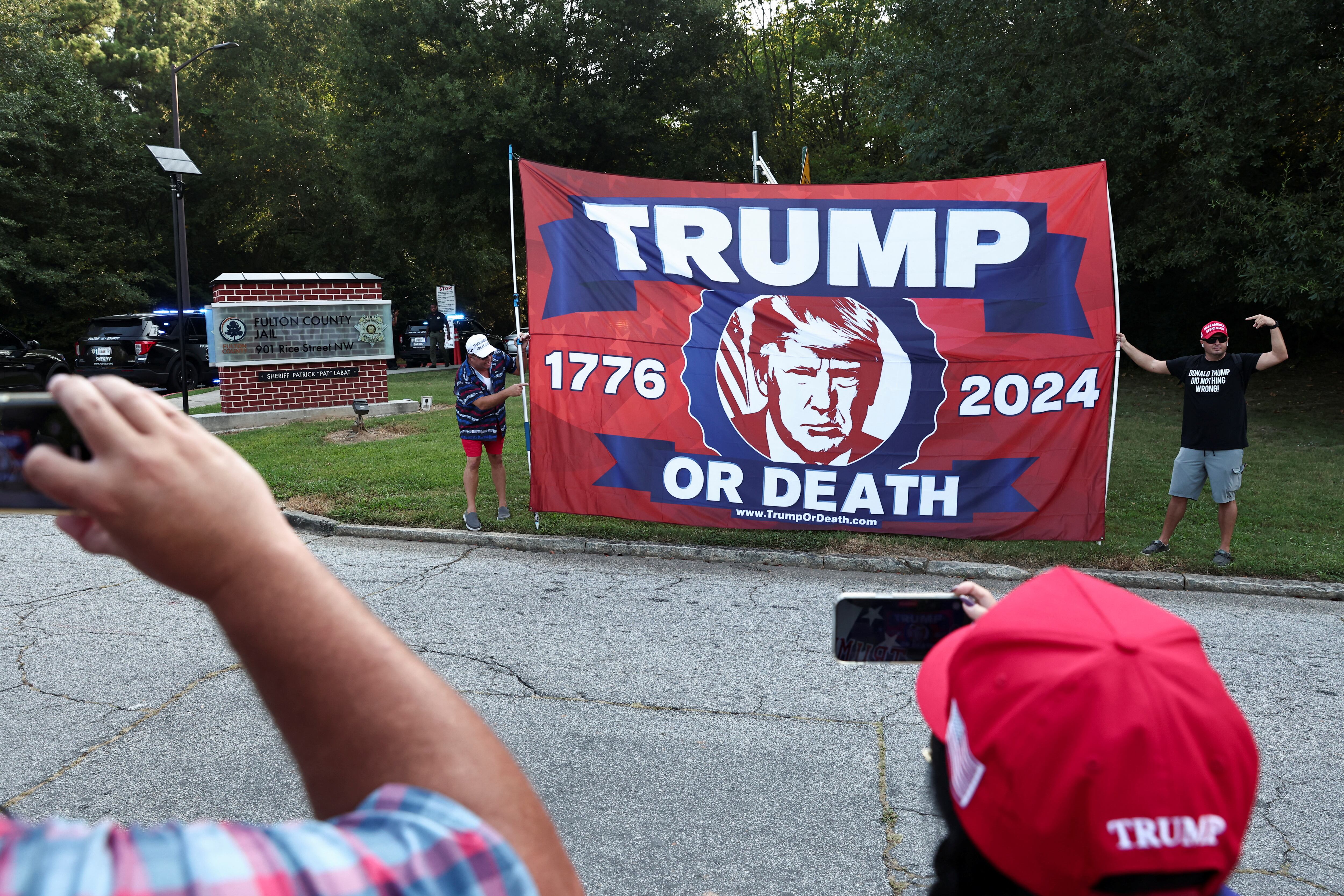 Manifestantes sostienen una pancarta en la entrada de la cárcel donde será procesado Trump. El expresidente negoció con sus abogados las condiciones de la entrega.