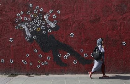 Una mujer camina junto a un mural pintado en el centro de Teherán (Irán).
