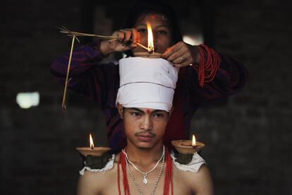 Un devoto sentado con lamparillas de aceite apoyadas en su cuerpo a modo de ofrenda durante las celebraciones por el festival Dashain en el templo Baramahini en Bhaktapur (Nepal).