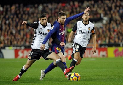 delantero argentino del FC Barcelona, Leo Messi (c), intenta llevarse el balón ante los jugadores del Valencia, el portugués Gonzalo Guedes (i) y Dani Parejo.
