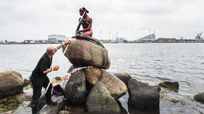 Un empleado municipal limpia la Sirenita en Copenhague, la mayor atracción turística de Dinamarca que ha aparecido pintada de rojo.