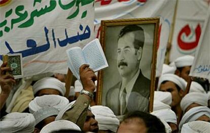 Estudiantes iraquíes muestran un Corán y una foto de Sadam Husein durante una marcha en Bagdad.