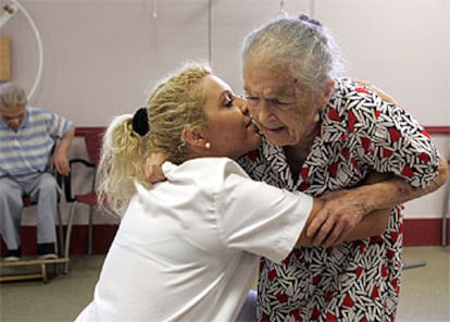 Josefa Moreno, en un centro de día de enfermos de alzheimer de la Cruz Roja. Al fondo, su marido, Luciano Fernández.