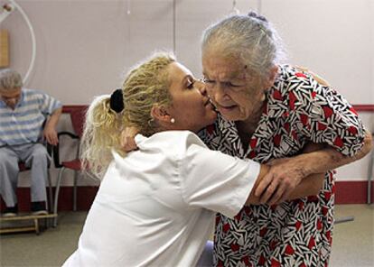 Josefa Moreno, en un centro de día de enfermos de alzheimer de la Cruz Roja. Al fondo, su marido, Luciano Fernández.