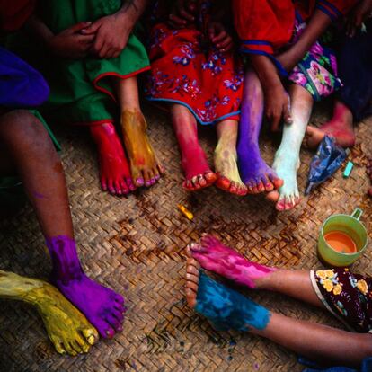 Los niños huicholes en México se reúnen para pintar sus pies con tiza y pinturas en polvo. La tierra sagrada de los huicholes, un lugar llamado Wirikuta, está actualmente en peligro por una empresa minera canadiense. Huichol, México, 2004.