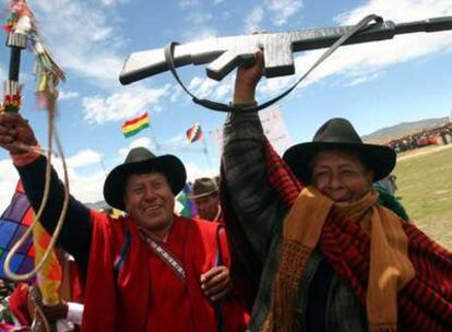 Dos miembros de los <i>ponchos rojos,</i> uno de ellos con un fusil simulado, vitorean al presidente Morales en Omasuyos.