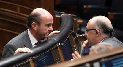 Caras de preocupación de los ministros de Economía y Hacienda, Luis de Guindos y Cristóbal Montoro, durante la sesión de control al Gobierno en el Congreso de los Diputados.