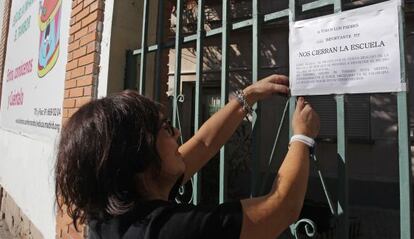 Una empleada coloca un cartel en la entrada de la Escuela Infantil El Tambor en San Fernando de Henares avisando del cierre y traslado inminente.