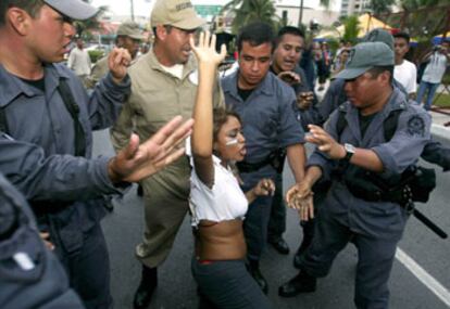 La policía reduce a una manifestante que intenta llegar a la sede de la cumbre de la OMC, en Cancún.