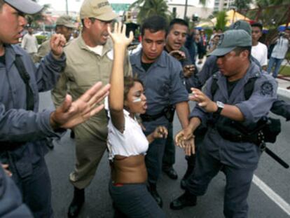 La policía reduce a una manifestante que intenta llegar a la sede de la cumbre de la OMC, en Cancún.