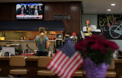 Una camarera hace una pausa en su restaurante para escuchar la declaración del exdirector del FBI, en Oceanside, California.