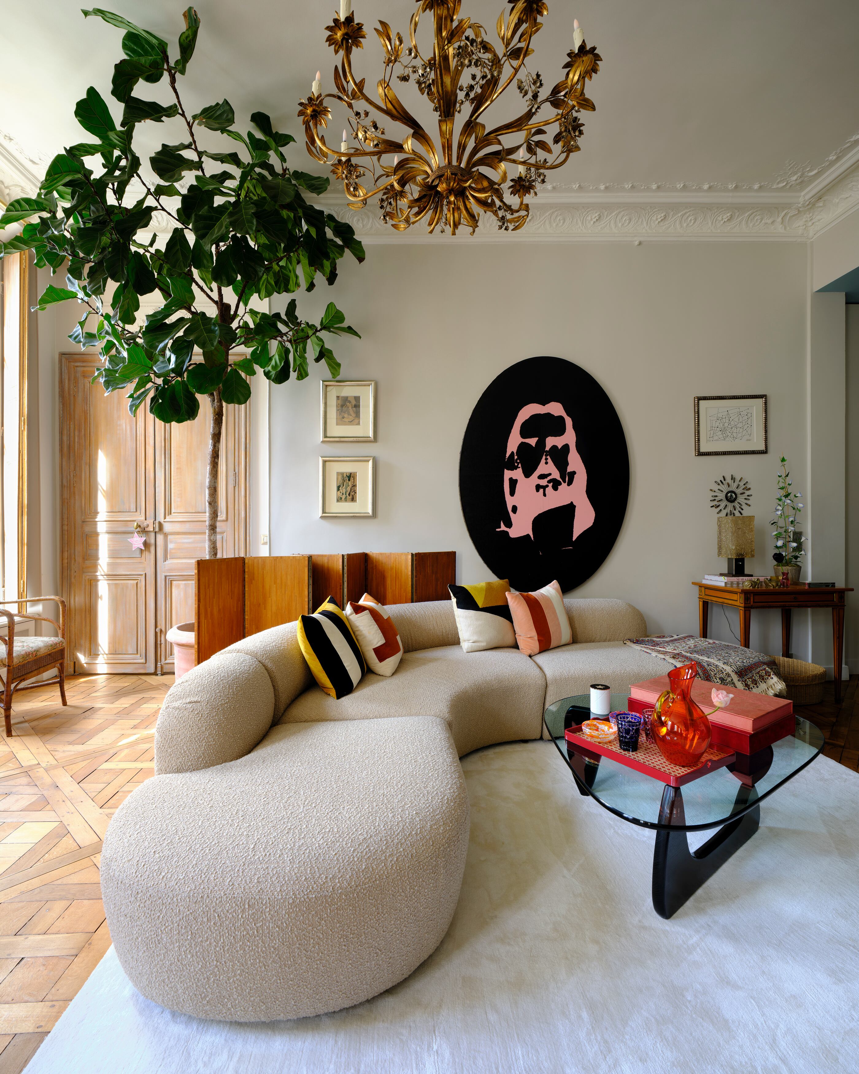 Uno de los salones de su piso, con un sofá italiano de los años sesenta y una obra de arte de Aaron Young. Sobre la mesa central, cristalería de Dior Maison. Detrás del sofá, un biombo de Jean-Michel Frank. Sobre la mesita, una lámpara, también de Frank.