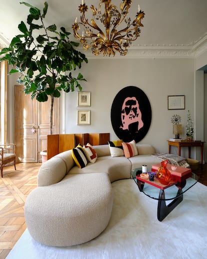 Uno de los salones de su piso, con un sofá italiano de los años sesenta y una obra de arte de Aaron Young. Sobre la mesa central, cristalería de Dior Maison. Detrás del sofá, un biombo de Jean-Michel Frank. Sobre la mesita, una lámpara, también de Frank.
