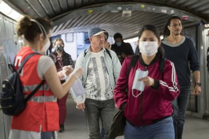 Reparto de mascarillas en la entrada de una estación del Metro de Barcelona.