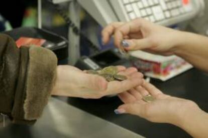 Una cajera ayuda a una cliente a contar monedas en un supermercado. EFE/Archivo