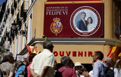 Turistas frente a una tienda de regalos con un cartel del Príncipe Heredero y la Princesa Letizia en el centro de Madrid.