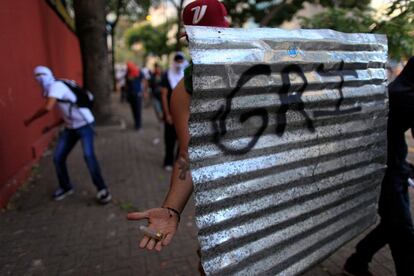 Un manifestante cubierto con una lámina de metal, a modo de escudo, muestra un casquillo de bala de goma disparado por la Guardia Nacional Bolivariana, durante los enfrentamientos en Caracas. 