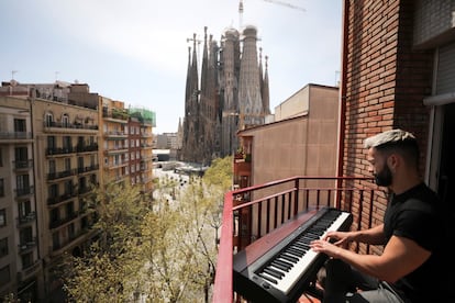 Alberto Gestoso toca el piano en el balcón de su vivienda cercana a la basílica de la Sagrada Familia de Barcelona. 