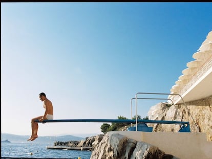 Muros encalados, roca, el azul del cielo, del mar, y un turista sobre un trampolín de piscina. Pocas combinaciones cromáticas funcionan mejor.