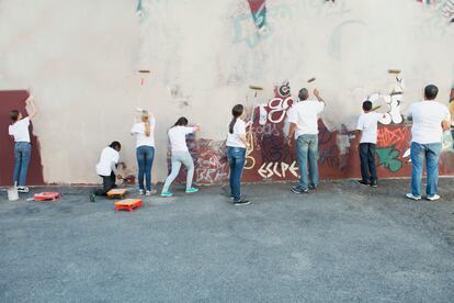 Voluntarios pintando pared grafiteada.