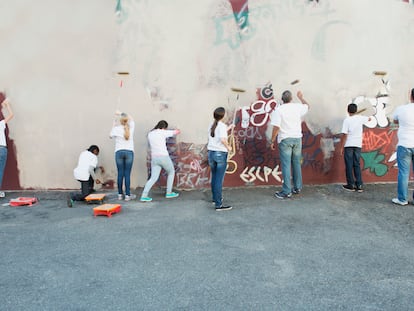 Voluntarios pintando pared grafiteada.