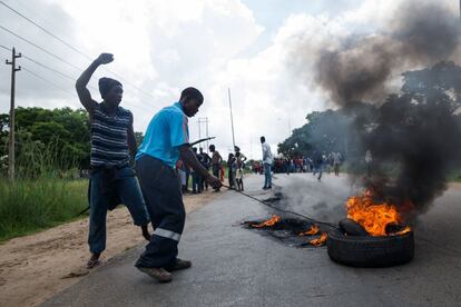 Un hombre prende un neumático durante los enfrentamientos con la policía que se han producido en la zona de Epworth, en Harare.