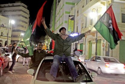 Manifestantes anti-Gadafi ondean la antigua bandera del reino de Libia en Bengasi.