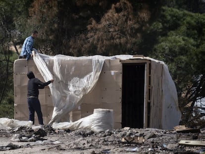 Dos temporeros reconstruyen una chabola calcinada, en un asentamiento de Palos de la Frontera (Huelva), el 12 de marzo.