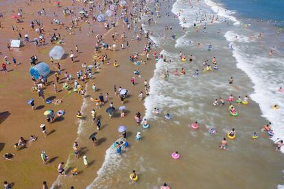 Bañistas se refrescan en una playa en Qingdao, provincia de Shandong (China). El presidente de Estados Unidos, Donald Trump, avanzó el jueves hacia el choque comercial total con el anuncio de nuevos aranceles para productos chinos por valor de 300.000 millones de dólares, a los que la potencia asiática respondió dejando caer su divisa con fuerza.