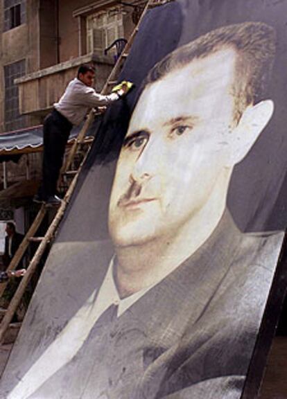 Un hombre limpia un enorme retrato de Bachar el Asad en Damasco.