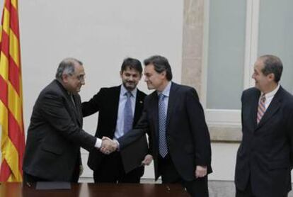 Artur Mas y Joaquim Nadal se saludan tras la firma del acuerdo de investidura en el Parlament.
