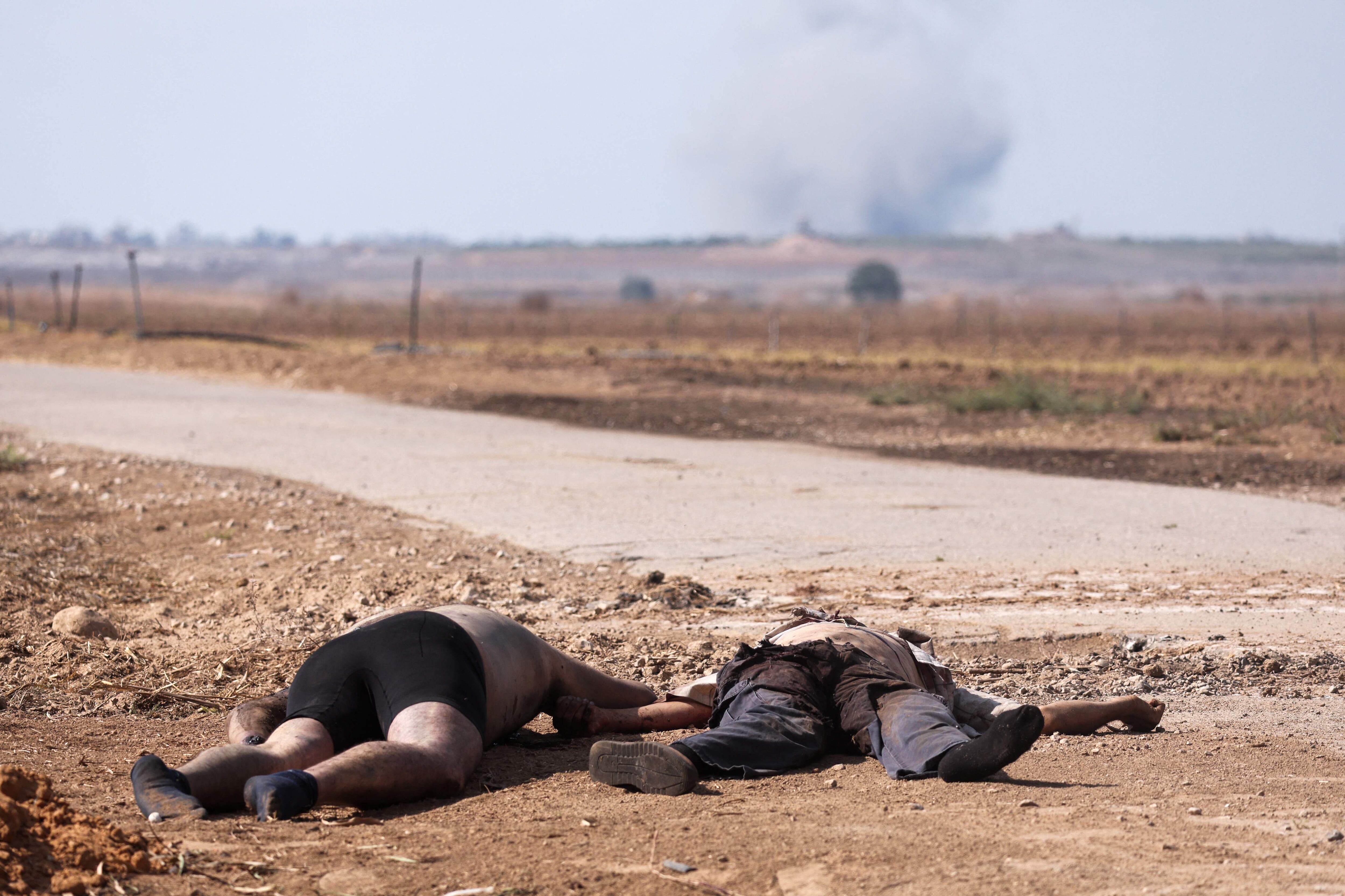 Dos cuerpos yacen en el suelo cerca de una carretera en el kibutz de Kfar Aza, al sur de Israel, en la frontera con la franja de Gaza.