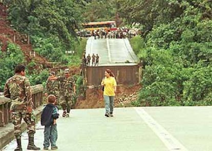 Soldados y civiles bolivianos observan el puente desplomado sobre el río Chapare.