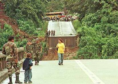 Soldados y civiles bolivianos observan el puente desplomado sobre el río Chapare.