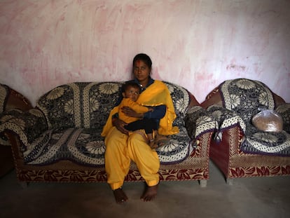 Sonu Bohra  sostiene en brazos a su hijo de dos años en su casa del pueblo de Sal, en el distrito de Champawat, en Uttarakhand (India).