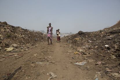 Madres caminan por los caminos que se dibujan entre las montañas de basura en el vertedero de 'Big Bomeh', en Freetown, Sierra Leona.
