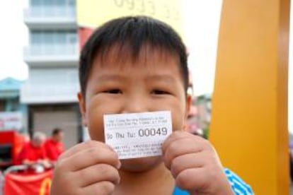 Un niño muestra un ticket en la apertura del primer McDonald's enHo Chi Minh, Vietnam.