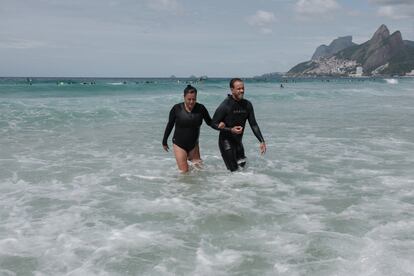 Rogerio Pessoa, fundador del proyecto Ondas Arpoador, sale del mar con Paula, una de sus alumnas.